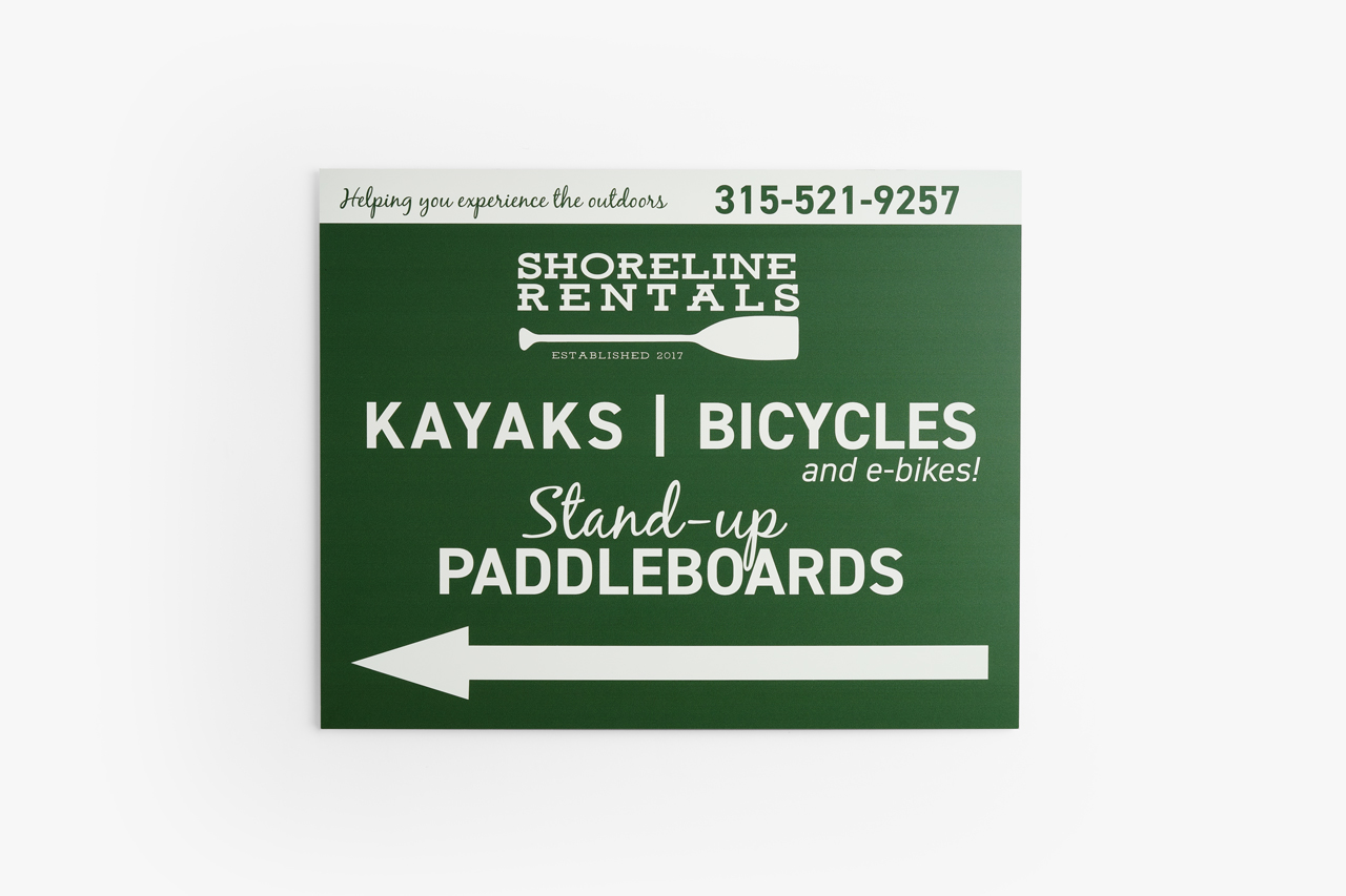 An aluminum sign printed with a dark green background and kayak and bike rental details.