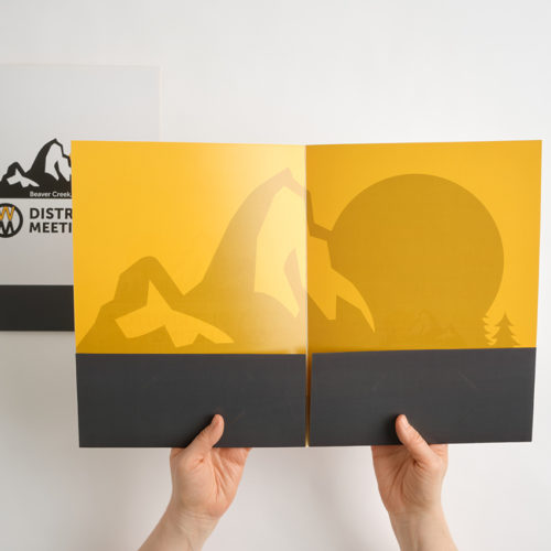 Two hands holding open a presentation folder printed with a yellow and black interior.