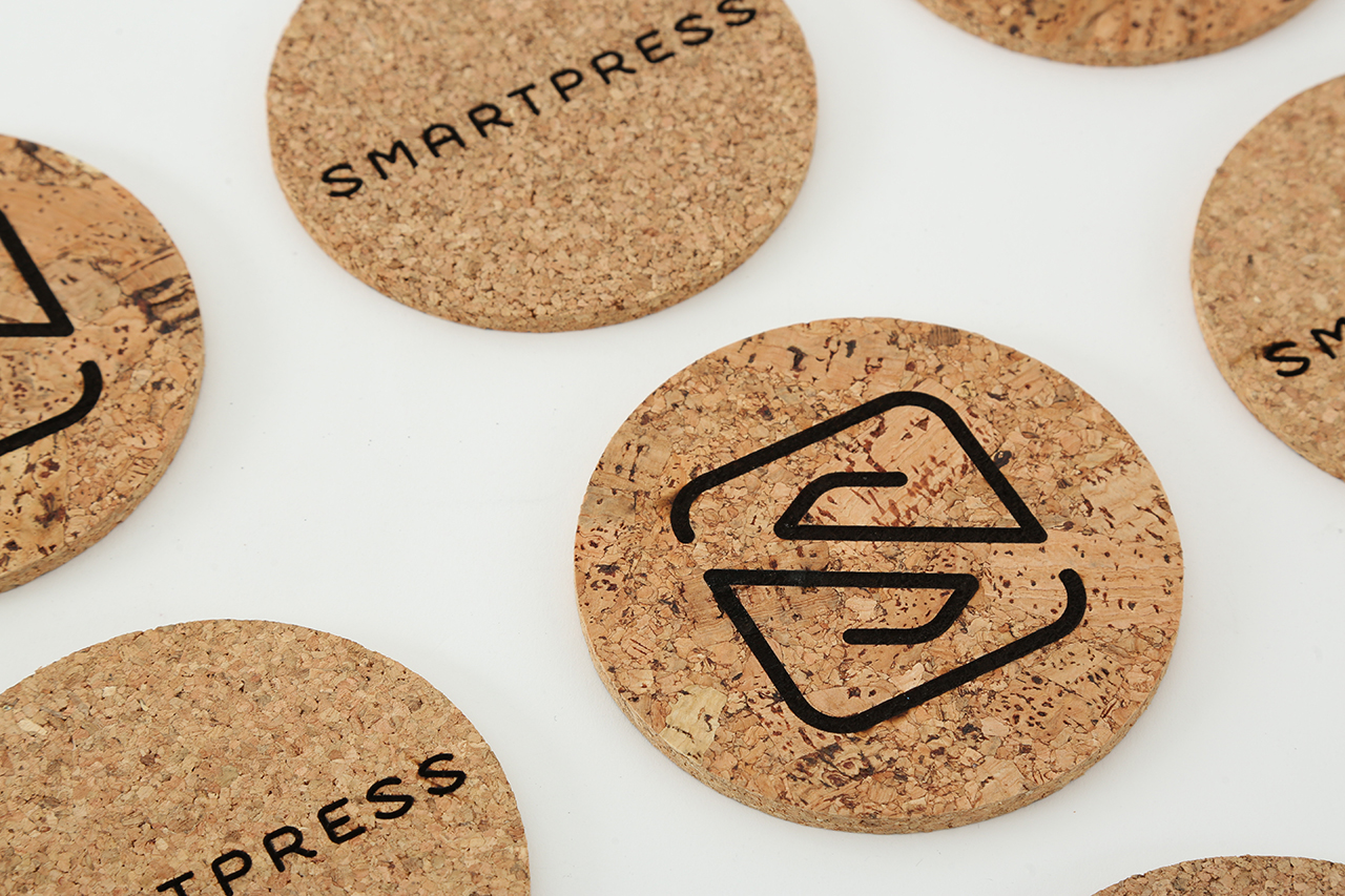 Custom Smartpress branded coasters with a cork design and black text.