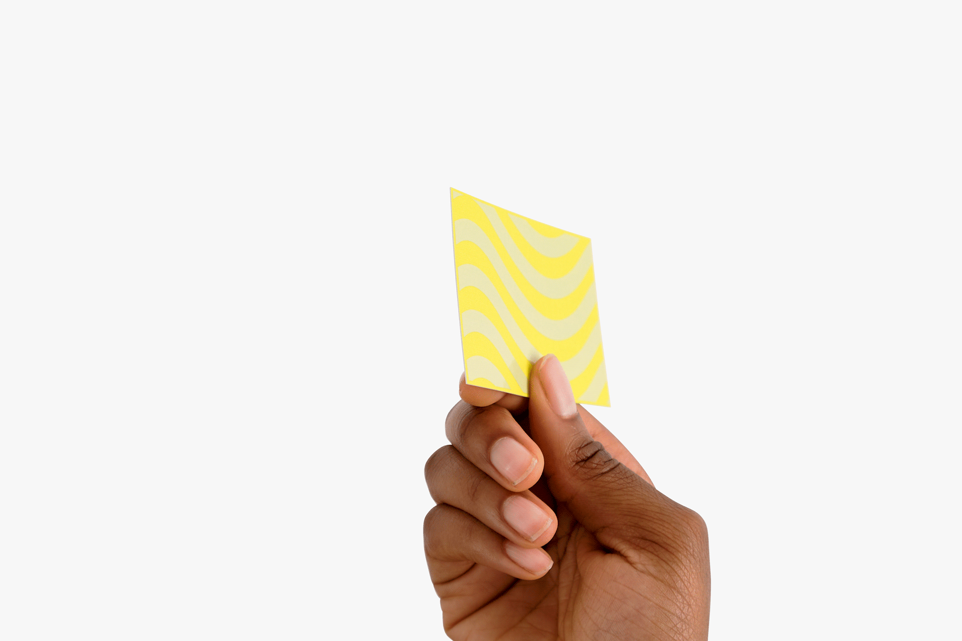 A hand holding a yellow business card finished with spot gloss.