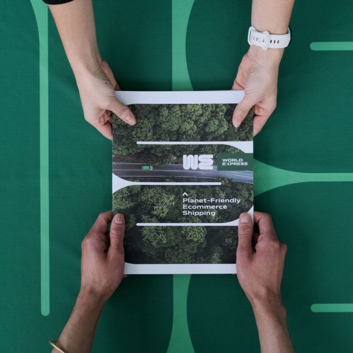 Four hands holding open a trade show product catalog with a green tree design.