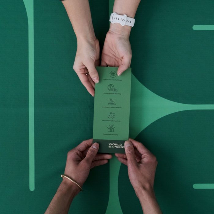 Four hands holding a custom rack card printed with a green design for a trade show.