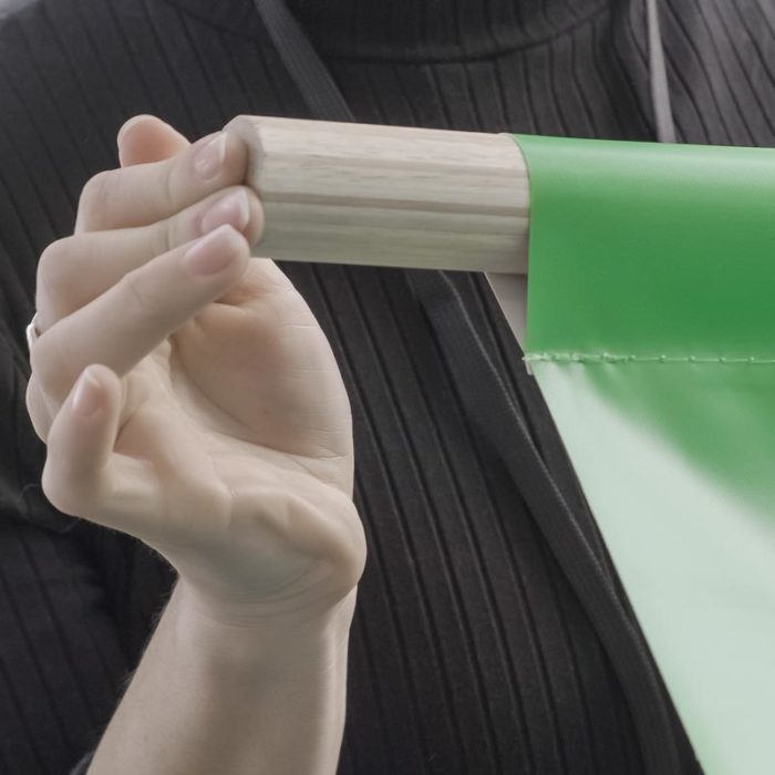 A hand pushing a wooden dowel into a pole pocket on a trade show banner.