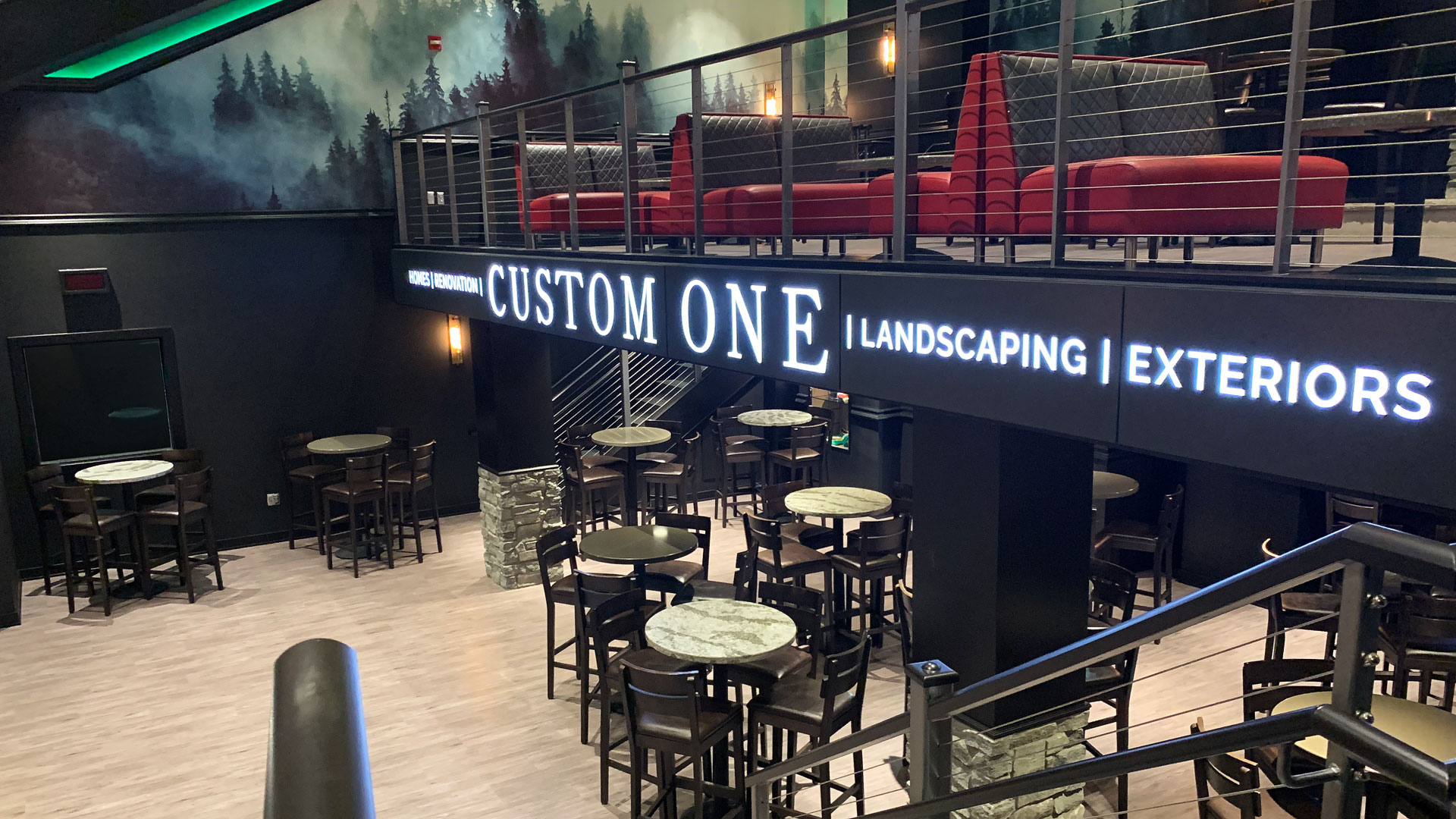 The On the Glass Club, with forest wall graphics, red booths and Custom One illuminated on a marquee.