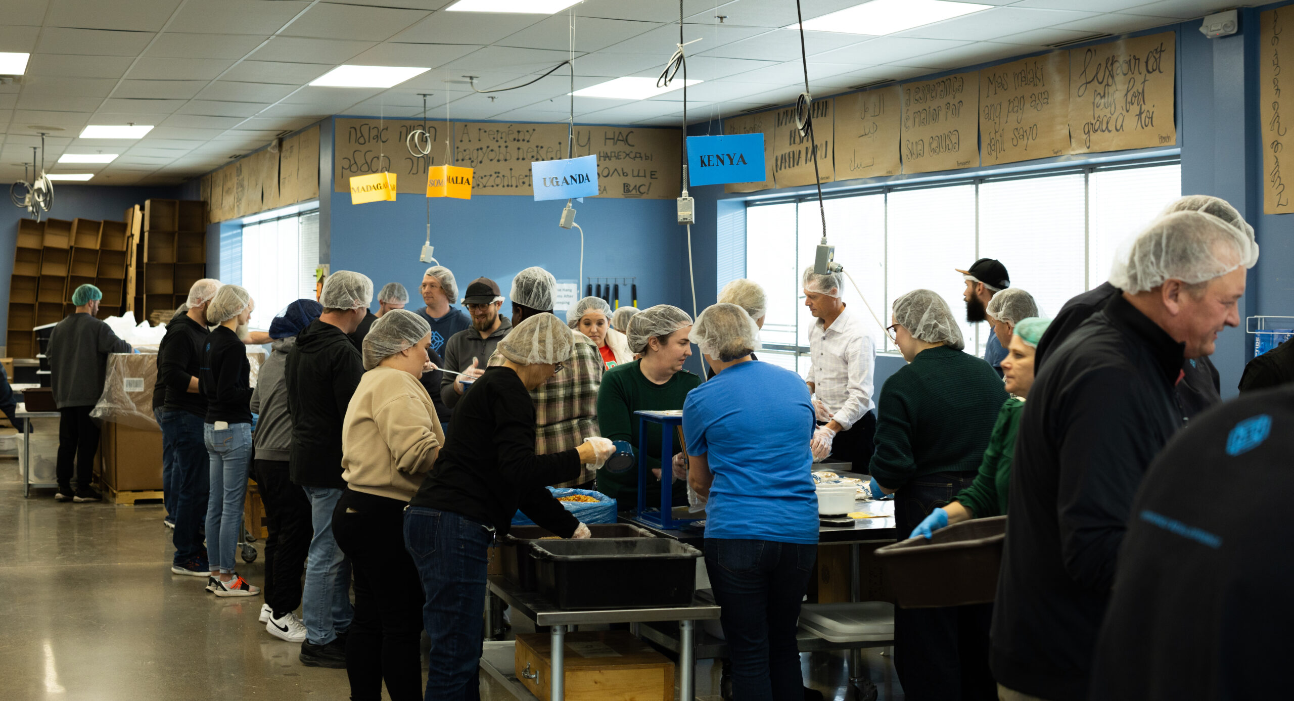 A group of people wearing hairnets packing food into bags and boxes for Feed My Starving Children.