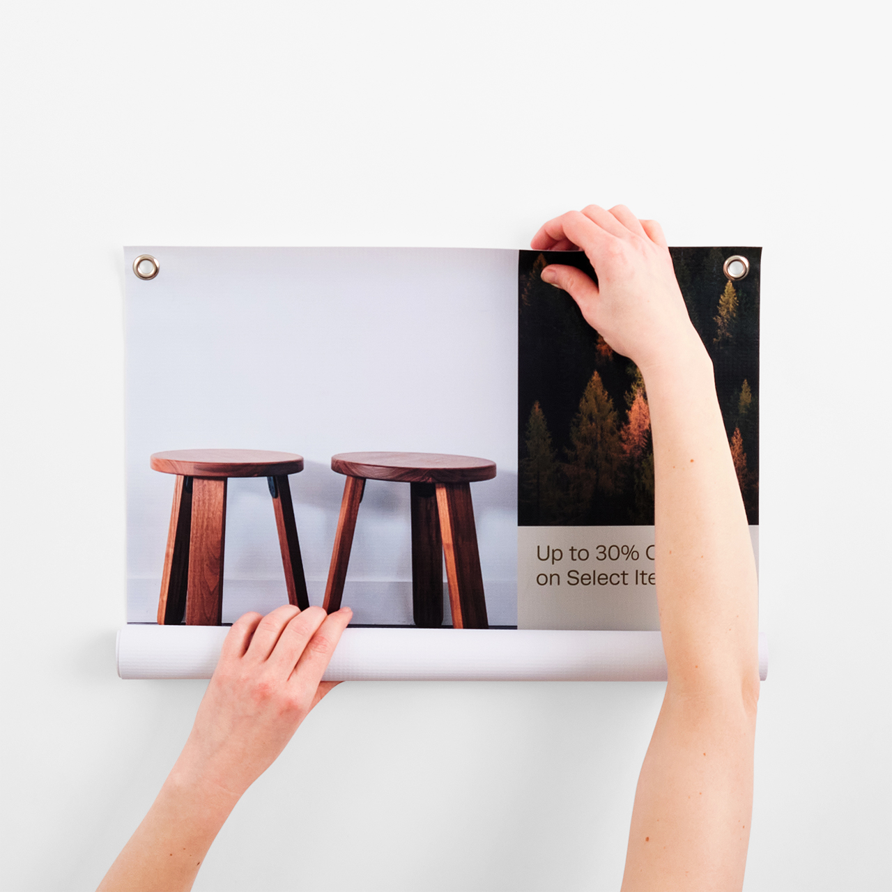 Two hands unrolling a sustainable banner printed with grommets in the corner and images of stools.