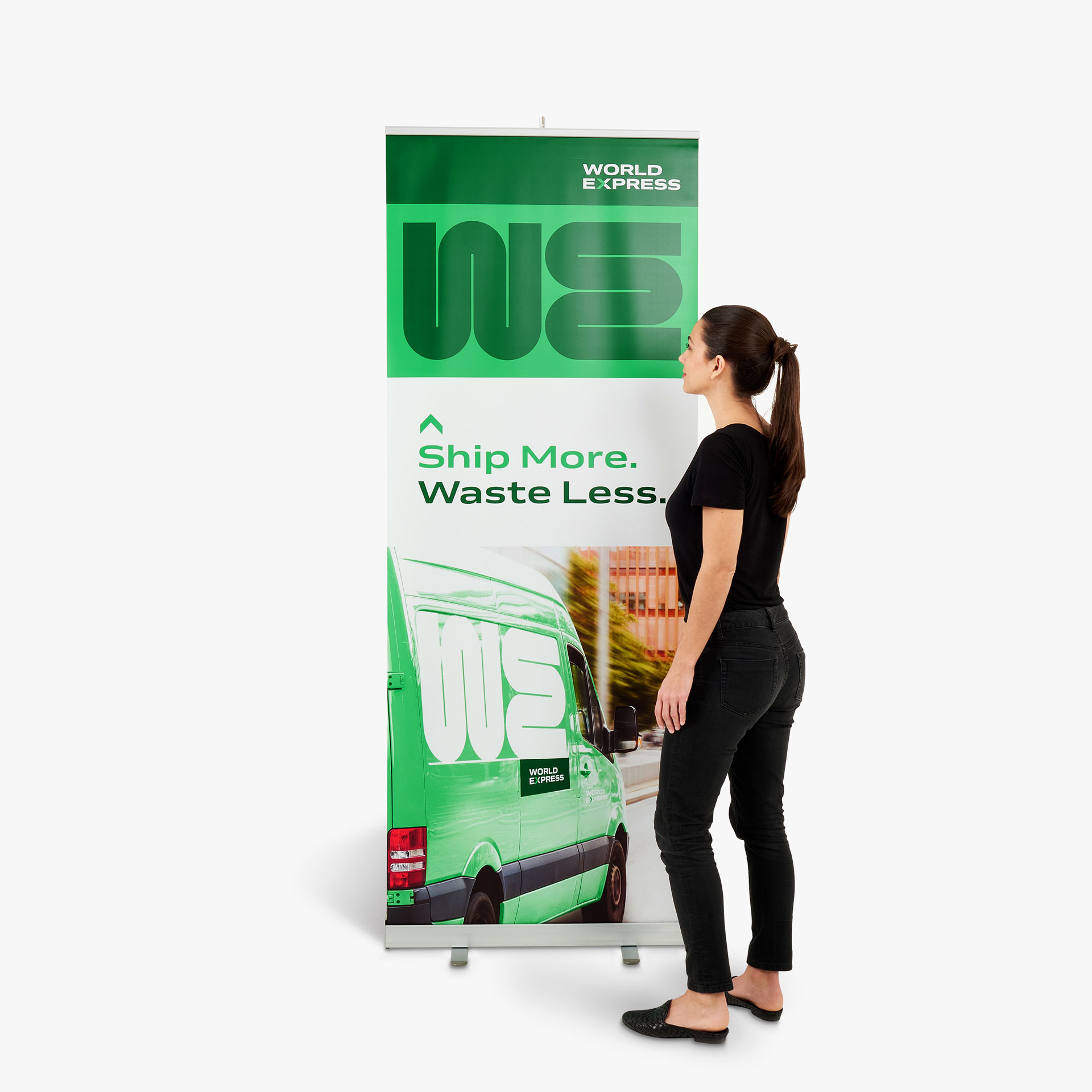 A woman in a black outfit standing in front of a retractable banner printed with a green, white and black design.