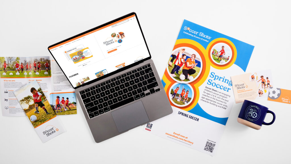 A birds-eye view picture of Soccer Shots printed material with a laptop demonstrate the ease of the brand's web-to-print software.