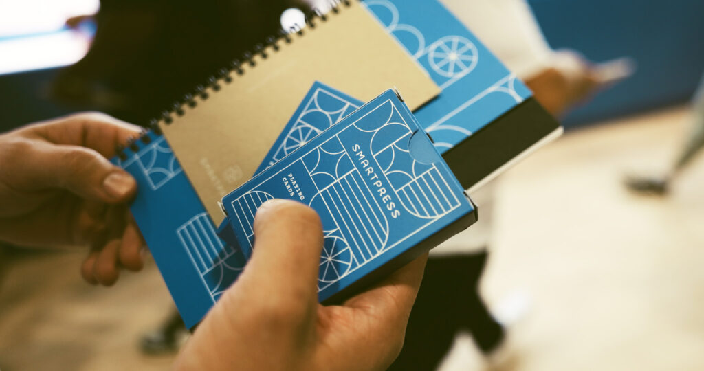 Two hands holding Smartpress' printed materials at Adobe Max.