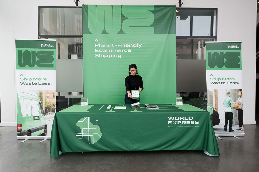 A woman standing at a trade show booth with coordinated printed banners, table cloth and brochures.