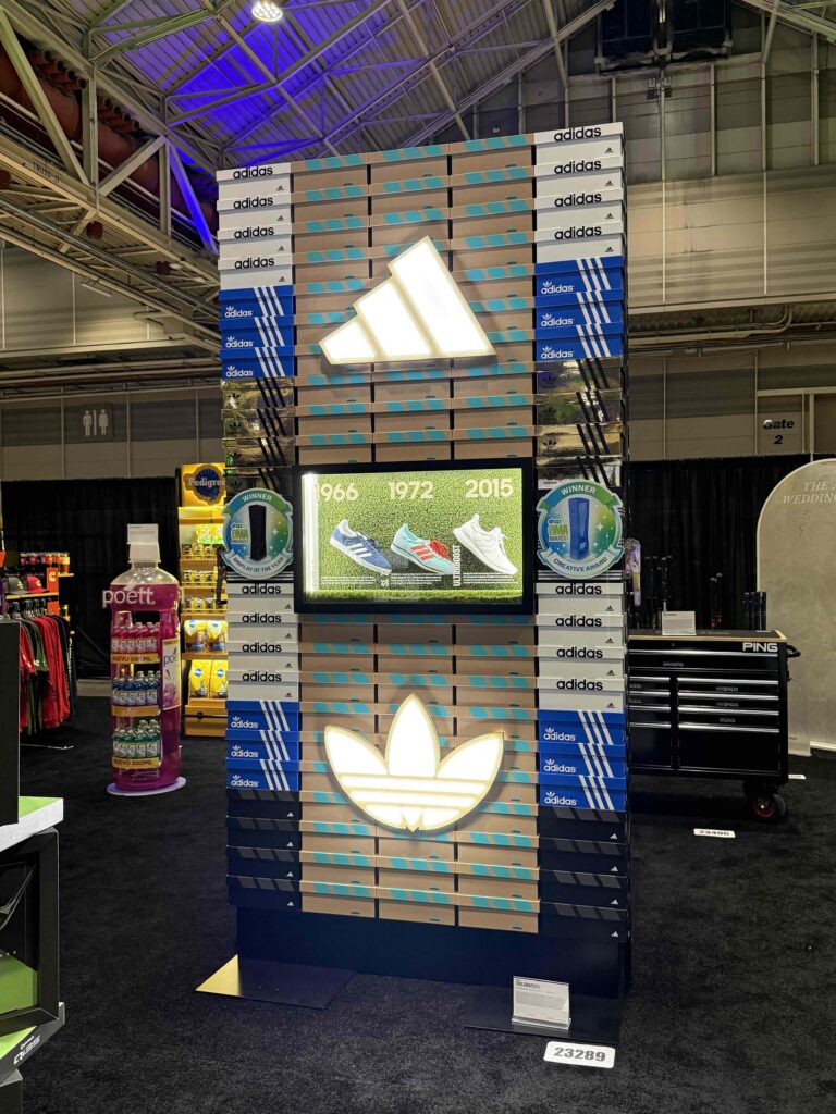 A stacked vertical shoebox-style tower display with internal LED lighting and recycled acrylic windows showcasing adidas heritage footwear.