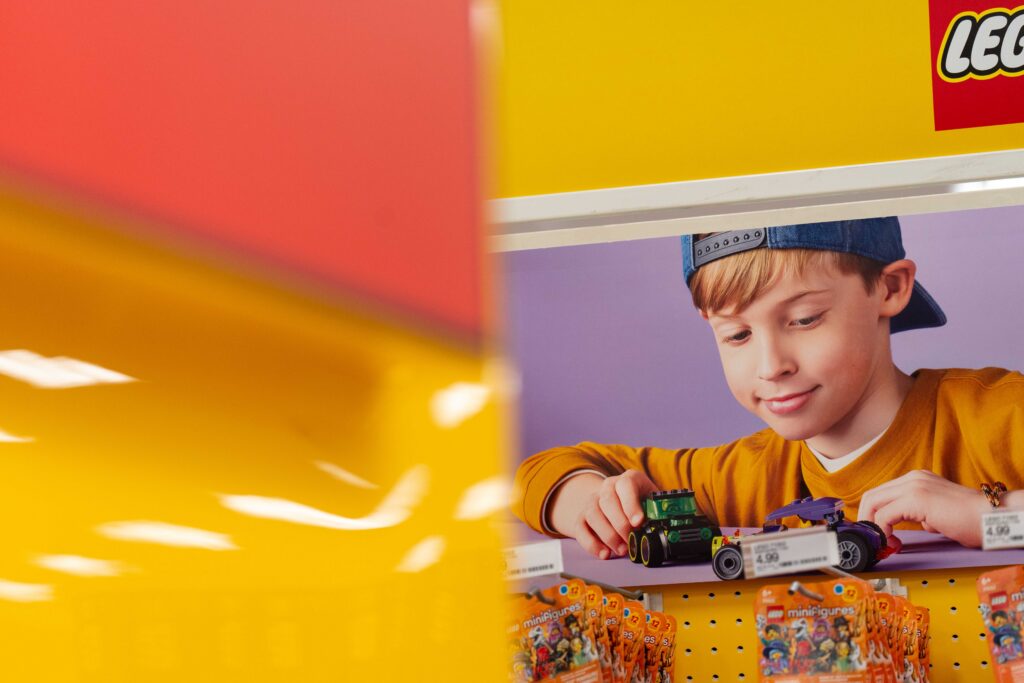 Close-up of a giant yellow LEGO brick fixture paired with vibrant graphic signage featuring a child playing with LEGOs.