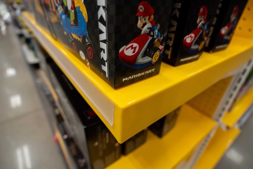 Side-angle view of a bright yellow retail shelf structure displaying boxed LEGO sets in a store aisle.