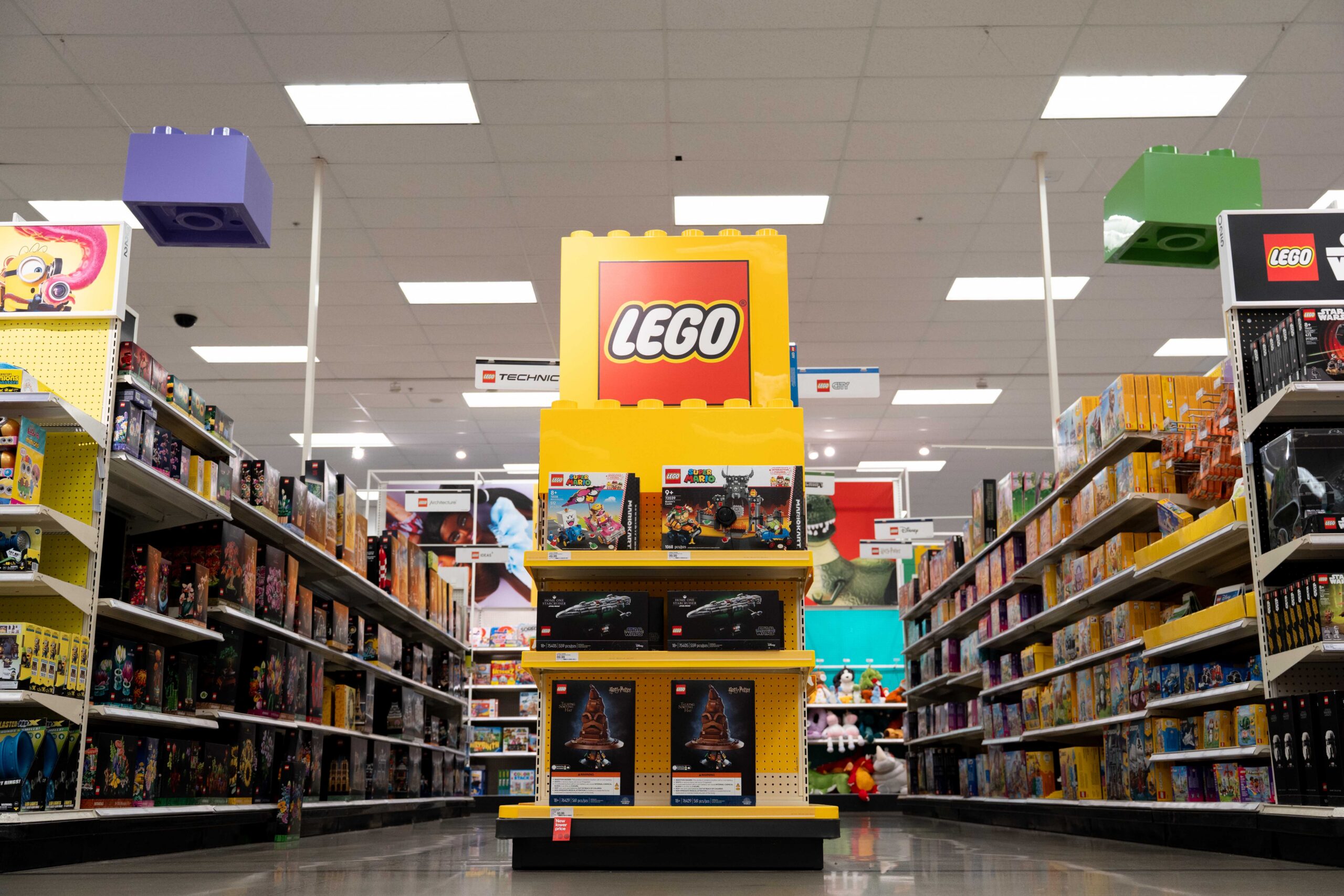 Endcap display featuring LEGO products, capped with a giant red LEGO logo display and oversized colorful LEGO bricks suspended from the store ceiling.