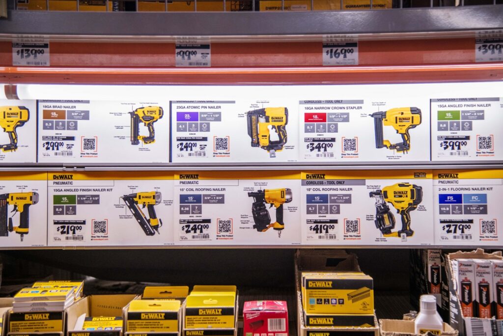 Organized Home Depot shelf bay displaying DEWALT power tool comparison cards with product specs, pricing, and QR codes for quick digital evaluation.