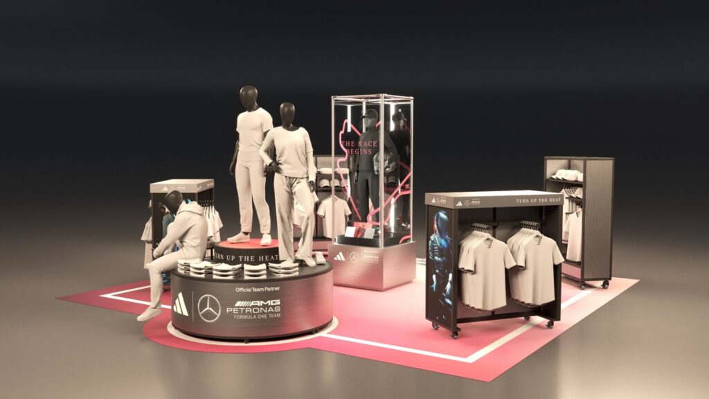 Immersive Mercedes-AMG PETRONAS F1 visual merchandising layout featuring mannequins, track-textured display stands, and branded apparel racks.
